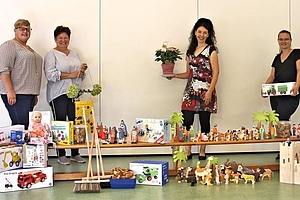 Vier Frauen zeigen die neuen Spielzeuge, die von der Spende gekauft wurden